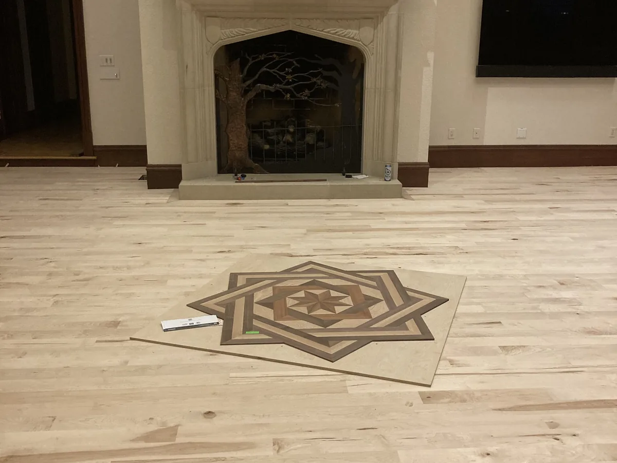 Star medallion inlay set into a new hardwood floor in front of a fireplace
