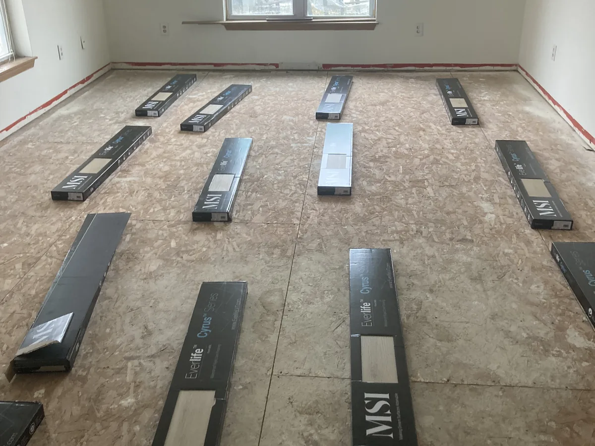 Boxes of vinyl plank laid out to acclimate over an existing tile floor